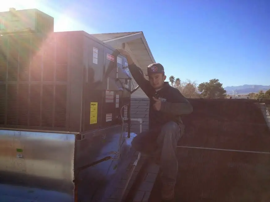 HVAC technician performing AC Tune-Up on a rooftop unit in Estelle
